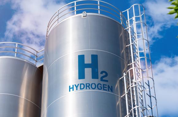 An image of a large, metal hydrogen storage tank that says 'H2 Hydrogen' on the side
