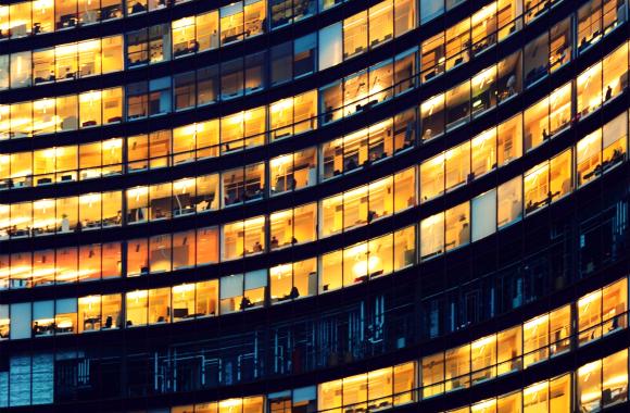 Office building exterior showing many floors of indoor lit offices