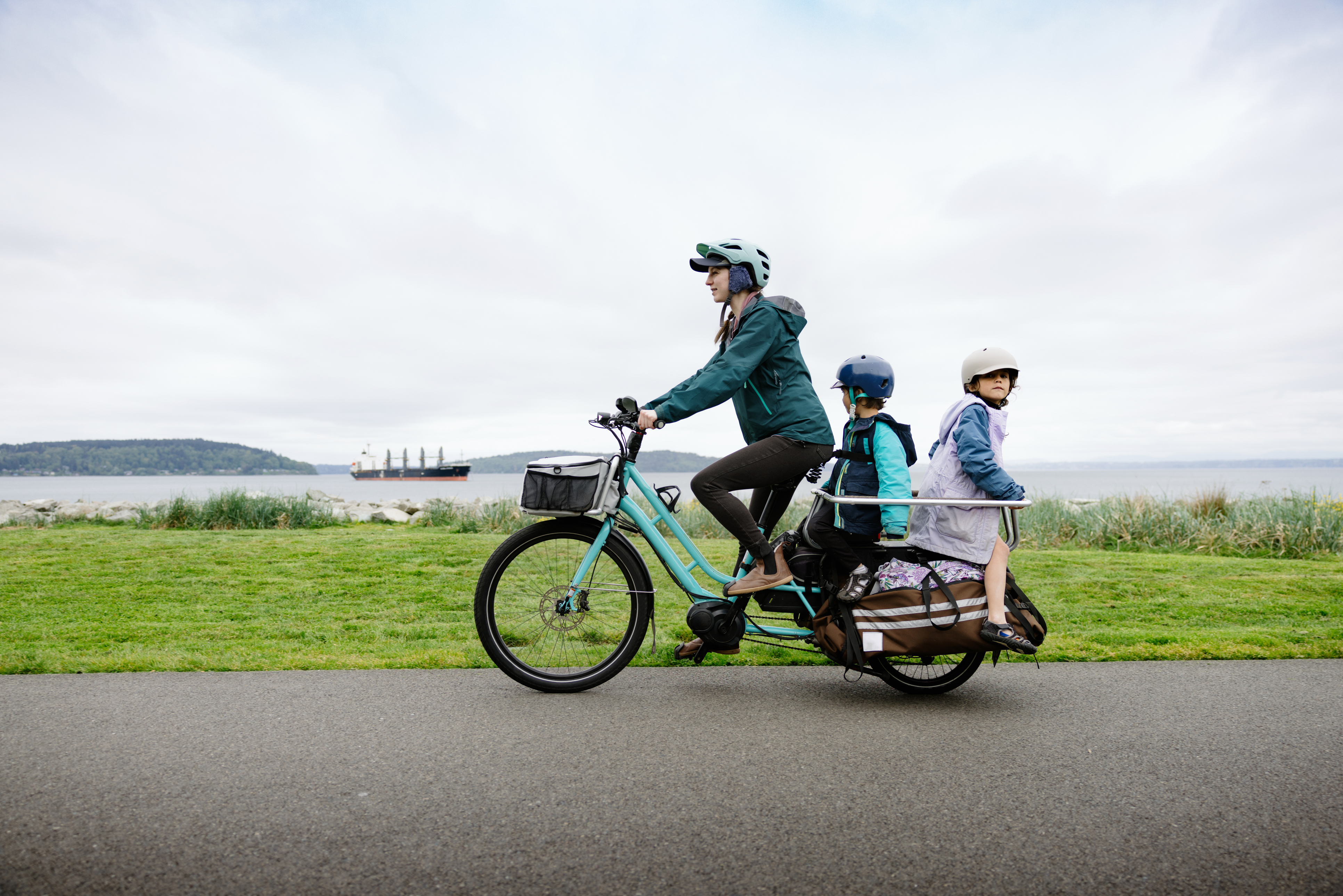 A family in Tacoma, Washington (USA) biking on a large electric-powered cargo bicycle.